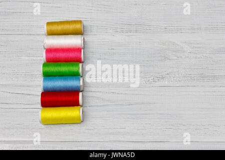 Bobbins with colorful threads on old wooden table background, Stock Photo