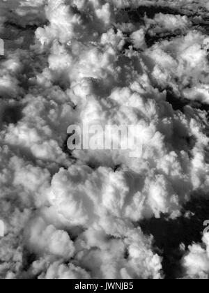 Monochrome layer of fluffy white cumulus clouds viewed from above at altitude from an airplane in flight in a full frame texture or cloudscape Stock Photo