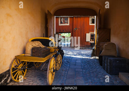 Vintage yellow wooden coach in old yard, Scandinavian style Stock Photo