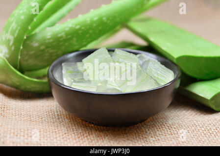 aloe vera gel in the black bowl and leaf on rustic fabric background Stock Photo