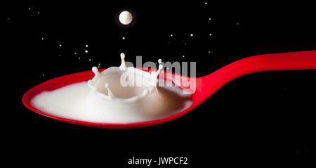White milk splashing into red spoon Stock Photo