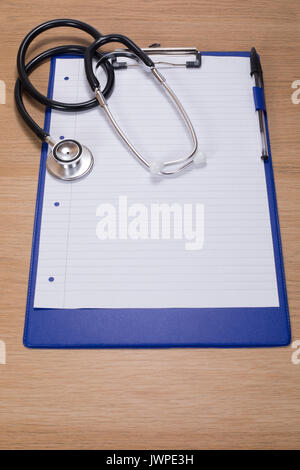 Stethoscope lying on a clipboard with blank paper on a wooden desk ...