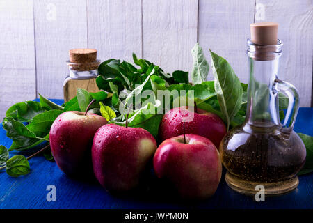 Apple cider vinegar. Three glass bottle on blue background. Red apples. Stock Photo