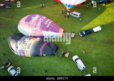 Hot air balloons begin to inflate on the launch site during the mass ascent, where balloons from all over the world gather at Ashton Court, Bristol, to take part in the Bristol International Balloon Fiesta. Stock Photo
