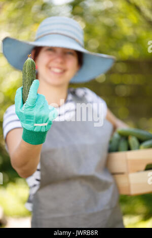Girl holds cucumber in hand Stock Photo
