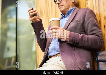 Closeup of contemporary senior man using modern smartphone outdoors Stock Photo