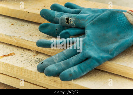 Workers gloves on a wood carpentry board Stock Photo