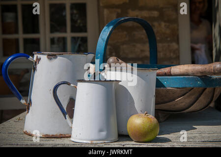 Enamel jugs on a table in an English country gardencountry Stock Photo