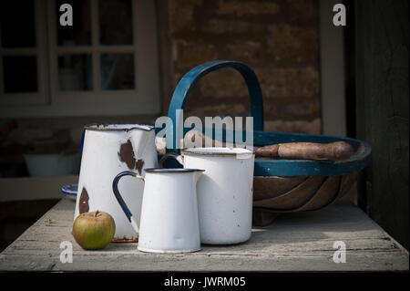 Enamel jugs on a table in an English country gardencountry Stock Photo