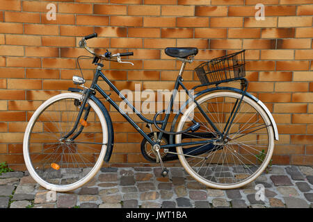 blue bicycle on cobblestone street leaning on brick wall Stock Photo