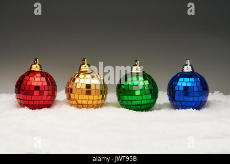 Four color christmas balls in a row in snow on gray background with copy space Stock Photo