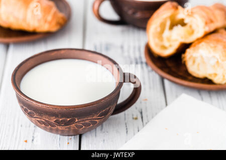 Cup of milk and fresh croissants on dark plate. White rustic table. Breakfast concept Stock Photo