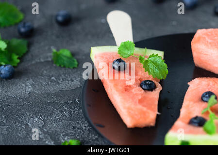 Watermelon popsicles stuffed with blueberry. Sweet refreshing snack concept. Close up on dark background Stock Photo