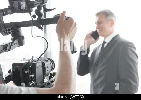 Videographer using steadycam, making video of businessman talking on phone Stock Photo
