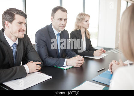 Business people sitting around meeting table, talking and working with documents Stock Photo