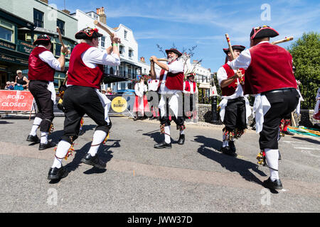 Traditional English folk dancers, Victory Morris group, dancing during Broadstairs Folk Week. Wearing crimson waistcoats and pirate hats, and dancing while holding wooden poles. Stock Photo