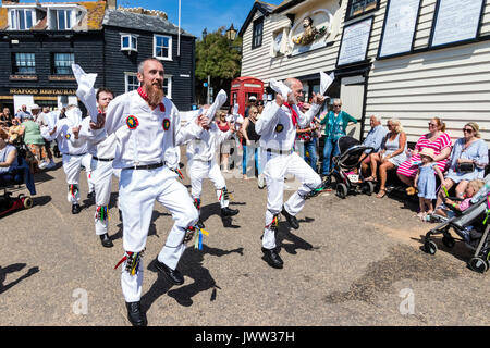 Traditional English folk dancers, Woodchurch Morris group, dancing on seafront harbour jetty during Broadstairs Folk Week. Wearing all white costume, waving white hankies, dancing in two rows. Stock Photo