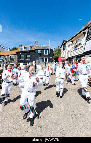 Traditional English folk dancers, Woodchurch Morris group, dancing on seafront harbour jetty during Broadstairs Folk Week. Wearing all white costume, waving white hankies, dancing in two rows. Stock Photo