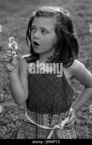 Black and white photo of a small girl holding a dandelion flower Stock Photo