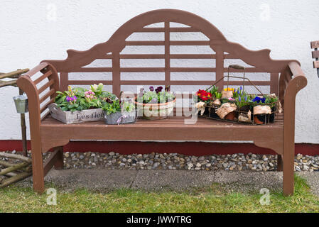 Primroses (Primula) and violets (Viola) in pots on a garden bench Stock Photo