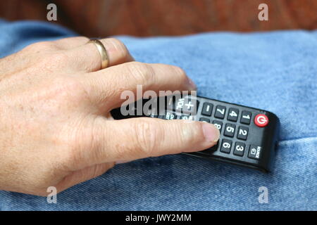 Man's hand holding tv remote control. Stock Photo