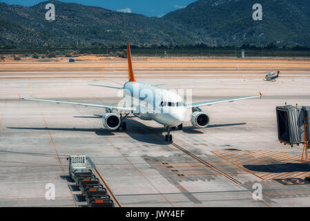 Beautiful white airplane on the runway in Dalaman airport. Landscape with big passenger airplane is taking off and mountains at bright sunny day Stock Photo