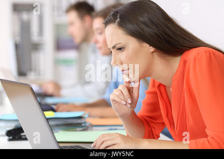 Side view portrait of a pensive businesswoman watching on line content at office Stock Photo