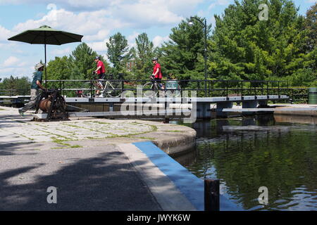Two cyclists crossing over the top gate at the lock at Carleton University, Rideau Canal, Ottawa, Ontario, Canada. Stock Photo