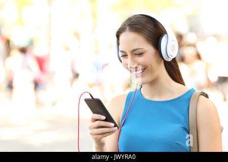 Portrait of a girl listening to music wearing headphones and walking on the street Stock Photo