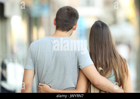 Back view portrait of a casual couple walking together on the street