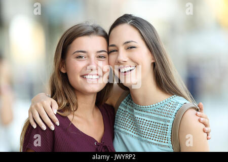 Two friends posing with perfect smiles and looking at camera on the street Stock Photo