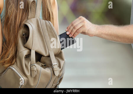 Close up of a thief hand stealing a phone from a bag on the street Stock Photo