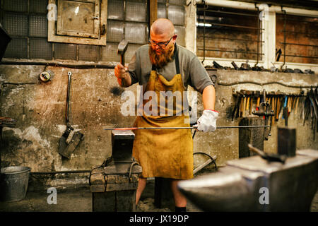 Blacksmith with beard working in his workshop Stock Photo