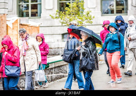 Quebec City, Canada - May 30, 2017: Closeup of tour group of people walking in heavy rain with umbrellas Stock Photo