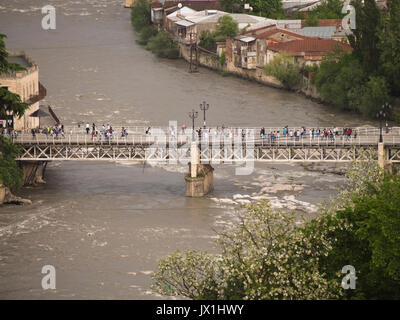 Looking down on the Rioni river running through Kutaisi Georgia, bridge filed with pedestrians on a festive day Stock Photo