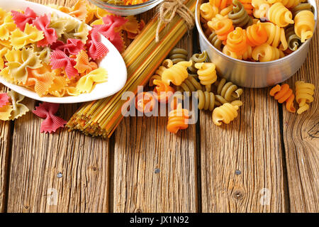 Various types of coloured pasta on a wooden background Stock Photo