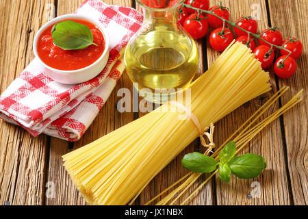 Still life of dried spaghetti, tomato puree and olive oil on wooden background Stock Photo