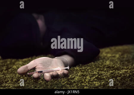 hand of young man lying on the floor with a syringe Stock Photo
