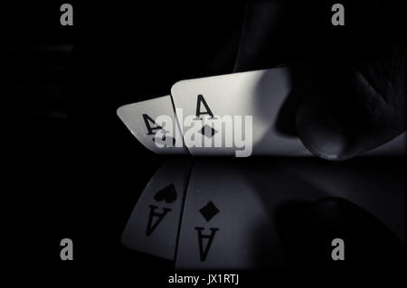 A pair of aces on a black background in hand from puckerman. Winning the game of cards. Playing cards in good combinations. black and white photo. Stock Photo