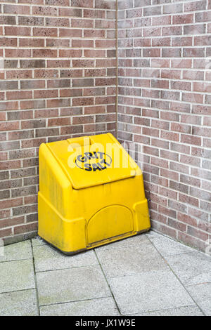 High-viz yellow plastic / polythene road and pavement salt/grit bin in the corner of a public pedestrian area. Stock Photo