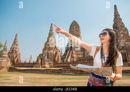 travel tourist woman holding map in Wai Chaiwatthanaram, Ayutthaya and looking and pointing for copyspace traveling in Asia smiling happy having fun i Stock Photo