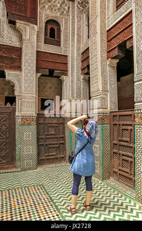 Woman taking pictures of the beautiful artwork inside the Koranic School in Meknes, Morocco Stock Photo