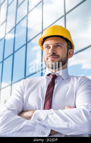 portrait of smiling professional architect in hard hat against building Stock Photo