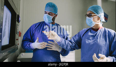 Two surgeons looking at screen and discussing while performing surgery in hospital operating room. Professional medics during surgery in operation the Stock Photo