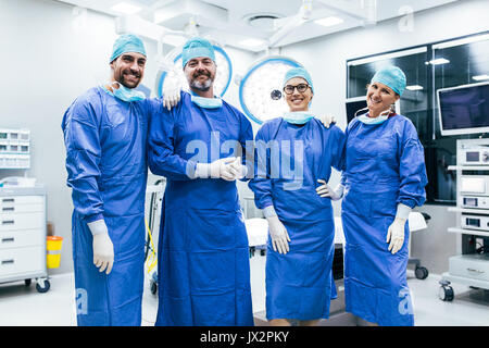 Portrait of successful medical workers in surgical uniform in operation theater. Team of surgeon standing in operating room, ready for next operation. Stock Photo