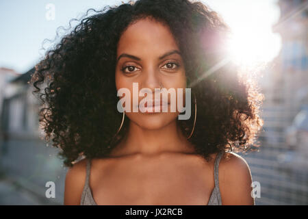 Close up portrait of beautiful young african woman with curly hair. Afro american female standing outdoors. Stock Photo