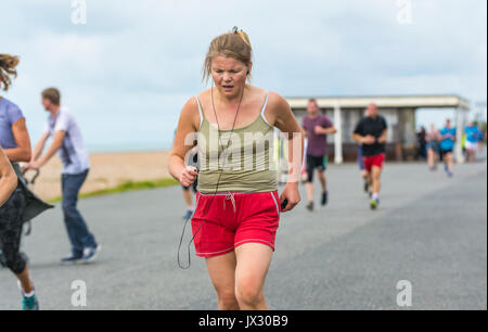 Young woman running on the weekly Vitality Parkrun event in Worthing, West Sussex, England, UK. Stock Photo