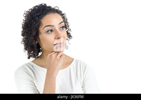 Short and curly haired woman is looking to the side. She is serious and with her hand on her chin. Girl is Brazilian and wears a neutral white outfit. Stock Photo