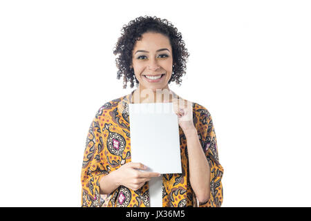 Enthusiastic girl is holding a blank paper with room for text. Short and curly haired woman wears yellow clothes and with floral pattern. Summer and t Stock Photo