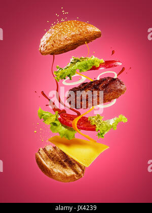 The hamburger with flying ingredients on rose background Stock Photo